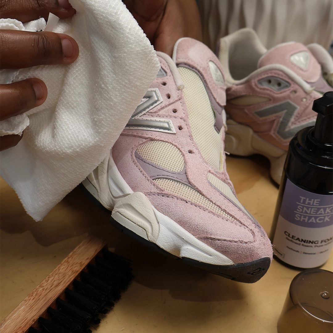 A pink New Balance running shoe being cleaned with The Sneaker Shack cleaning foam
