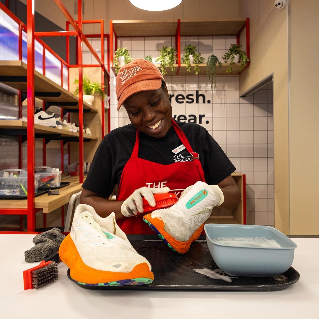A Sneaker Shack technician cleaning a pair of running shoes in-store